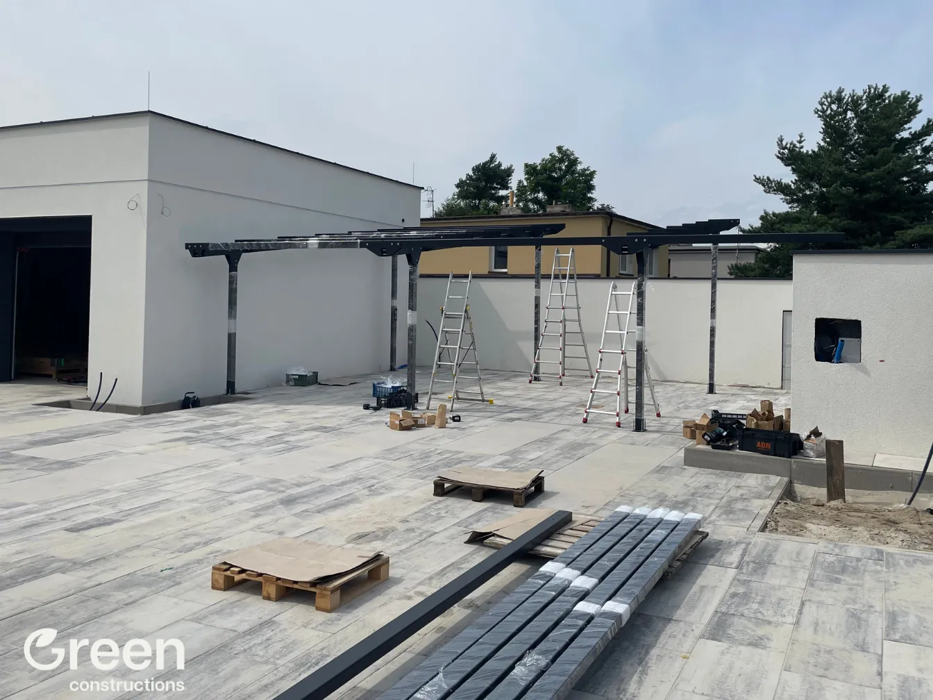 Wiata fotowoltaiczna 16 kWp w czasie budowy - ustawione zostały główne słupy oraz pierwsze belki poprzeczne, pomalowane na antracytowy kolor